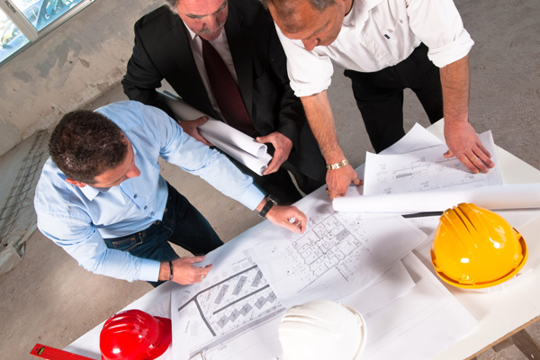 Three construction executives looking at drawings