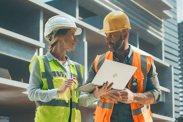 Man Woman Outdoors on a construction site looking at a laptop THUMBNAILImage