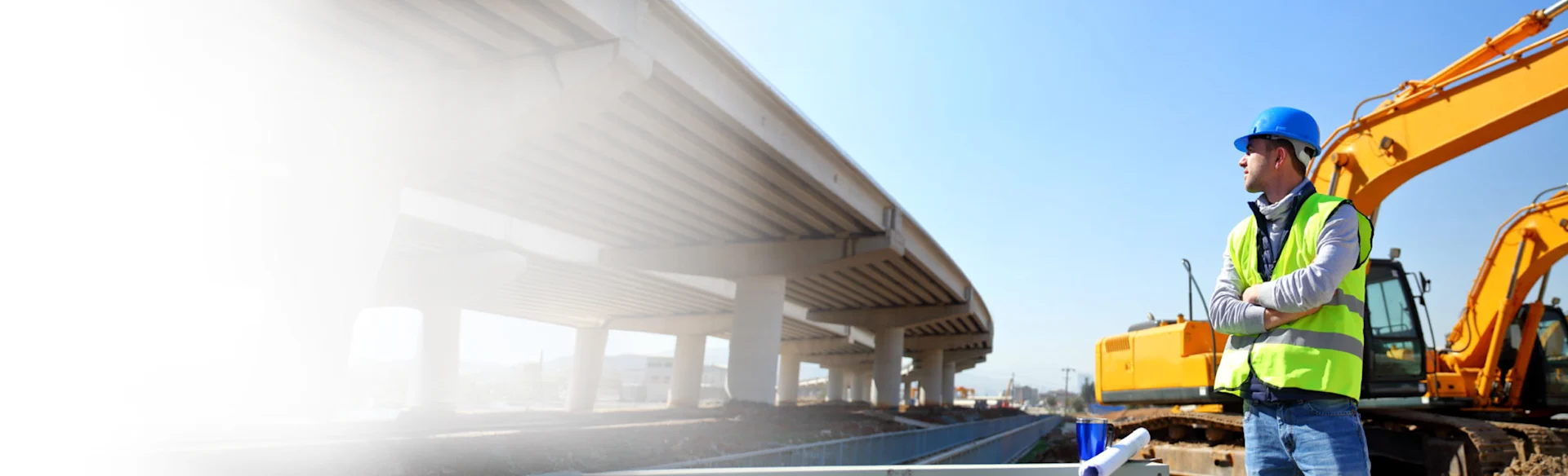 Male construction worker standing looking at a highway 1200x800