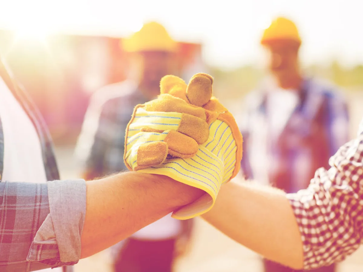 Two construction workers gripping hands THUMBNAIL