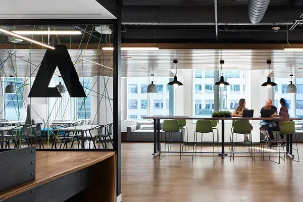 Three employees talking at a desk in the distance THUMBNAIL
