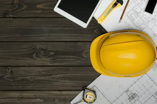 Over head shot of yellow helmet and drawings and iPad on a table THUMBNAIL