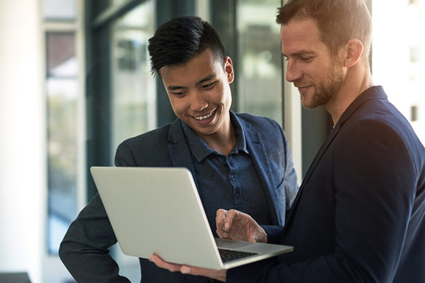 Two employees looking at a laptop THUMBNAIL