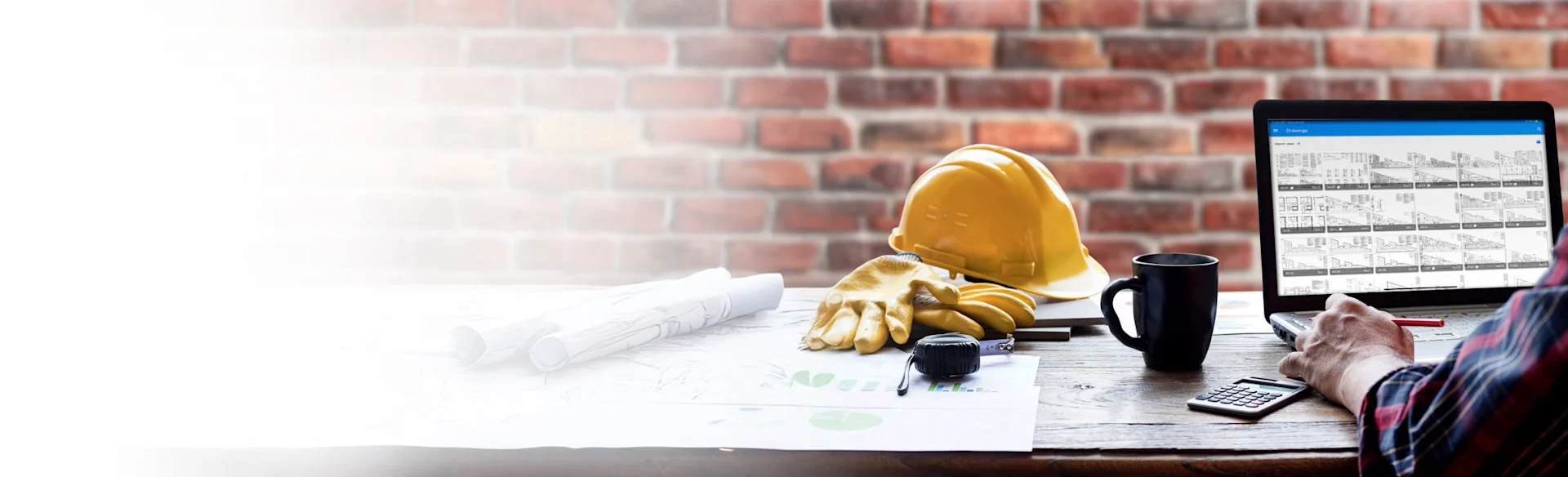 Yellow construction on a desk next to a laptop with drawings 1200x900
