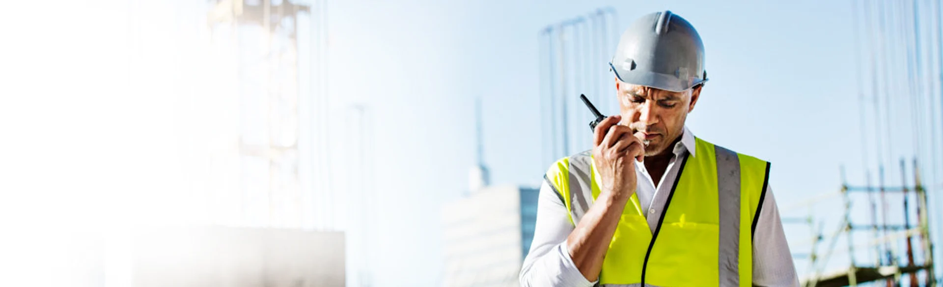 Construction worker on a walkie talkie with a crane in the background 1200x800