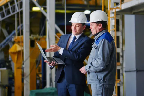 Two executives on a site looking at a laptop THUMBNAIL