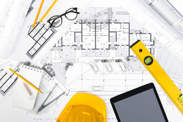 Overhead shot of yellow helmet and drawings on a table THUMB