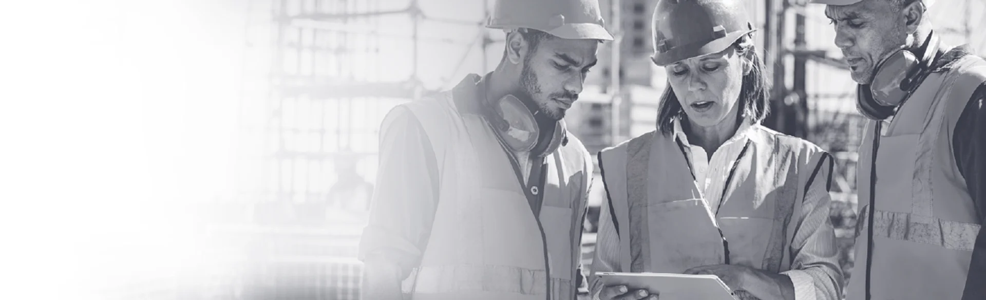 Three construction workers on site looking at an iPad