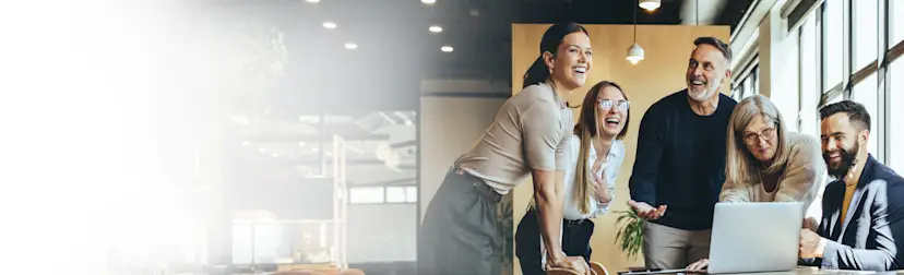 Five employees happy around a laptop