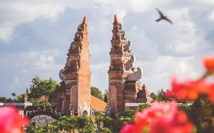 A temple with two towers and flowers in the background.