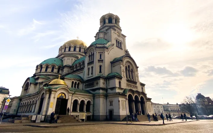 A large church with gold domes in the middle of a city.