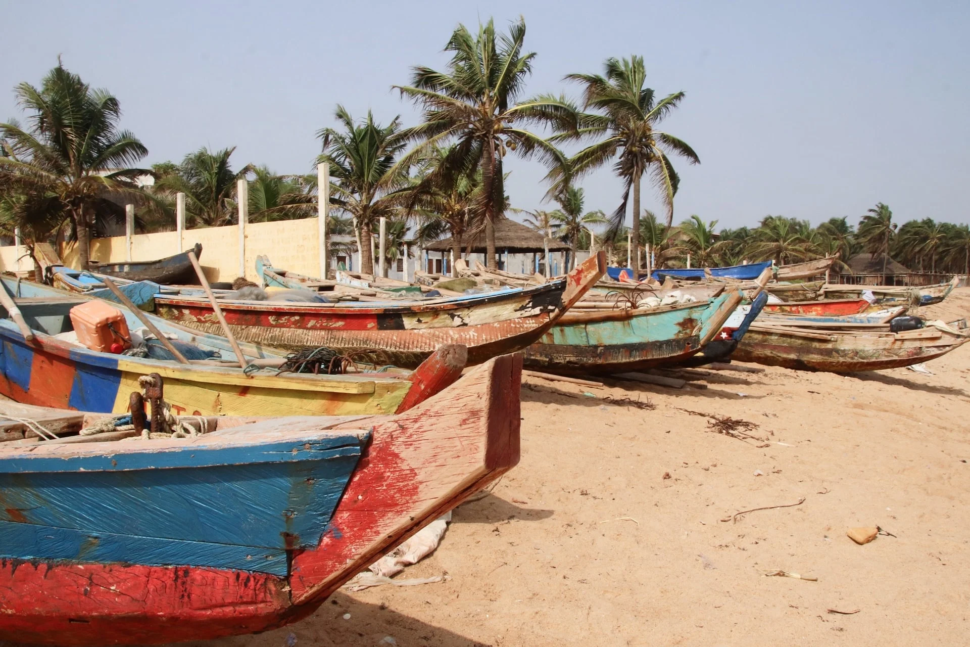 A group of colorful fishing boats on a sandy beach.