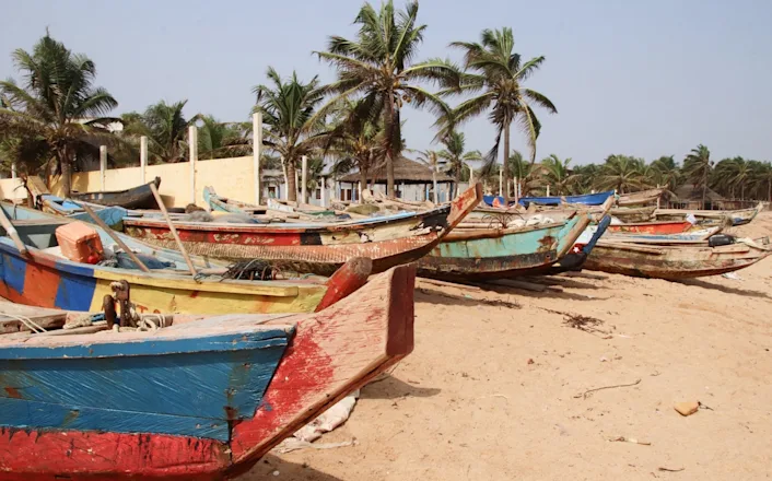 A group of colorful fishing boats on a sandy beach.