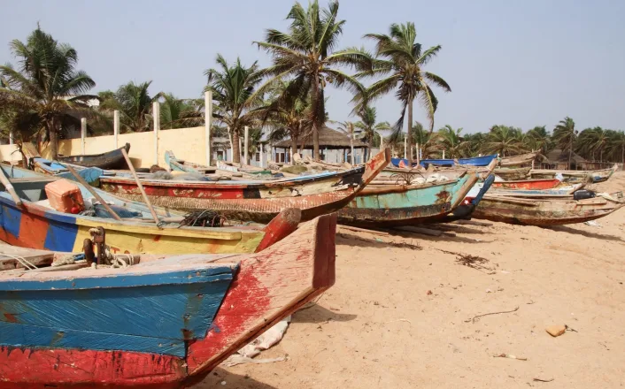 A group of colorful fishing boats on a sandy beach.