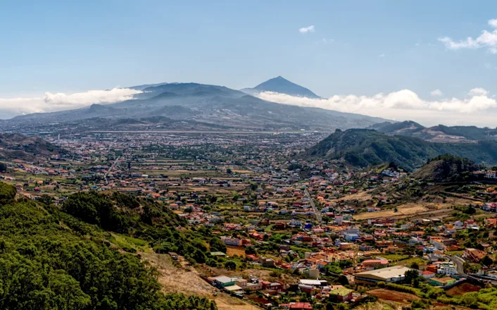 A view of a town with a mountain in the background.