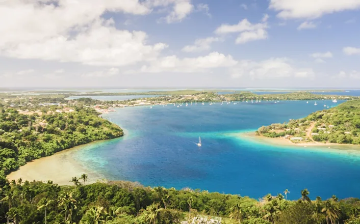 An aerial view of a tropical island with blue water and green trees.