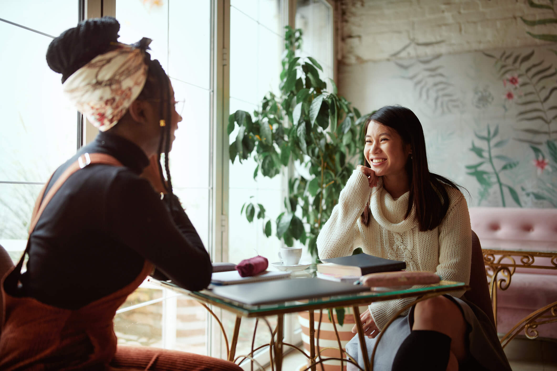 Two women talking at a table in a coffee shop.