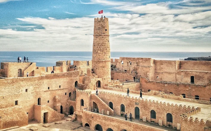 A view of an old castle with towers and a flag.
