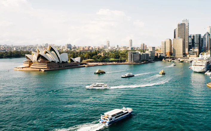 The sydney opera house and sydney harbour with boats in the background.