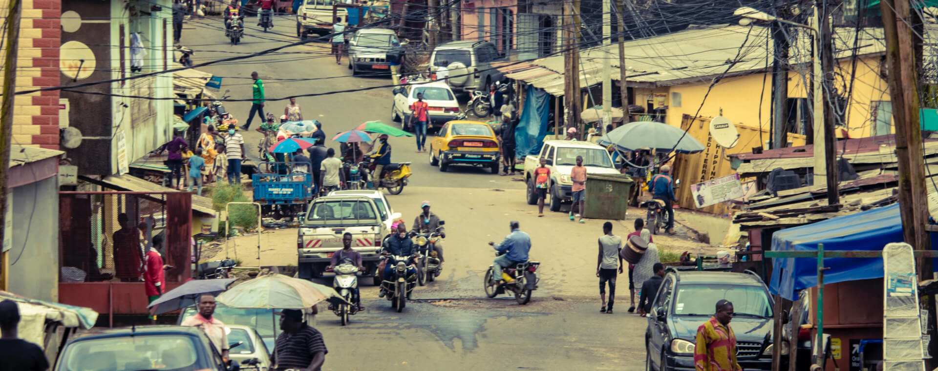 A street in nigeria with a lot of people and motorcycles.