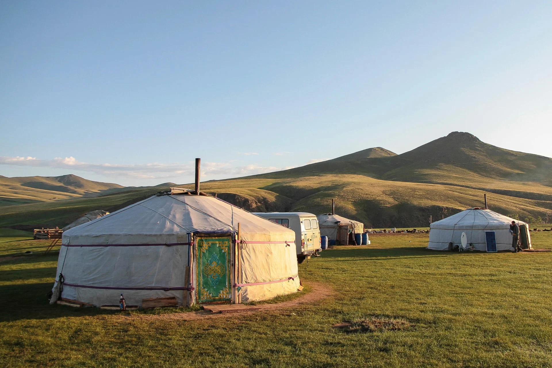 A group of yurts in the middle of a grassy field.