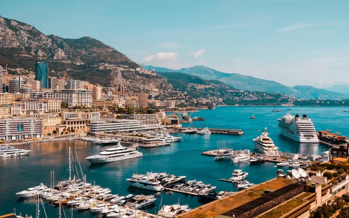 The port of monaco with boats docked and mountains in the background.