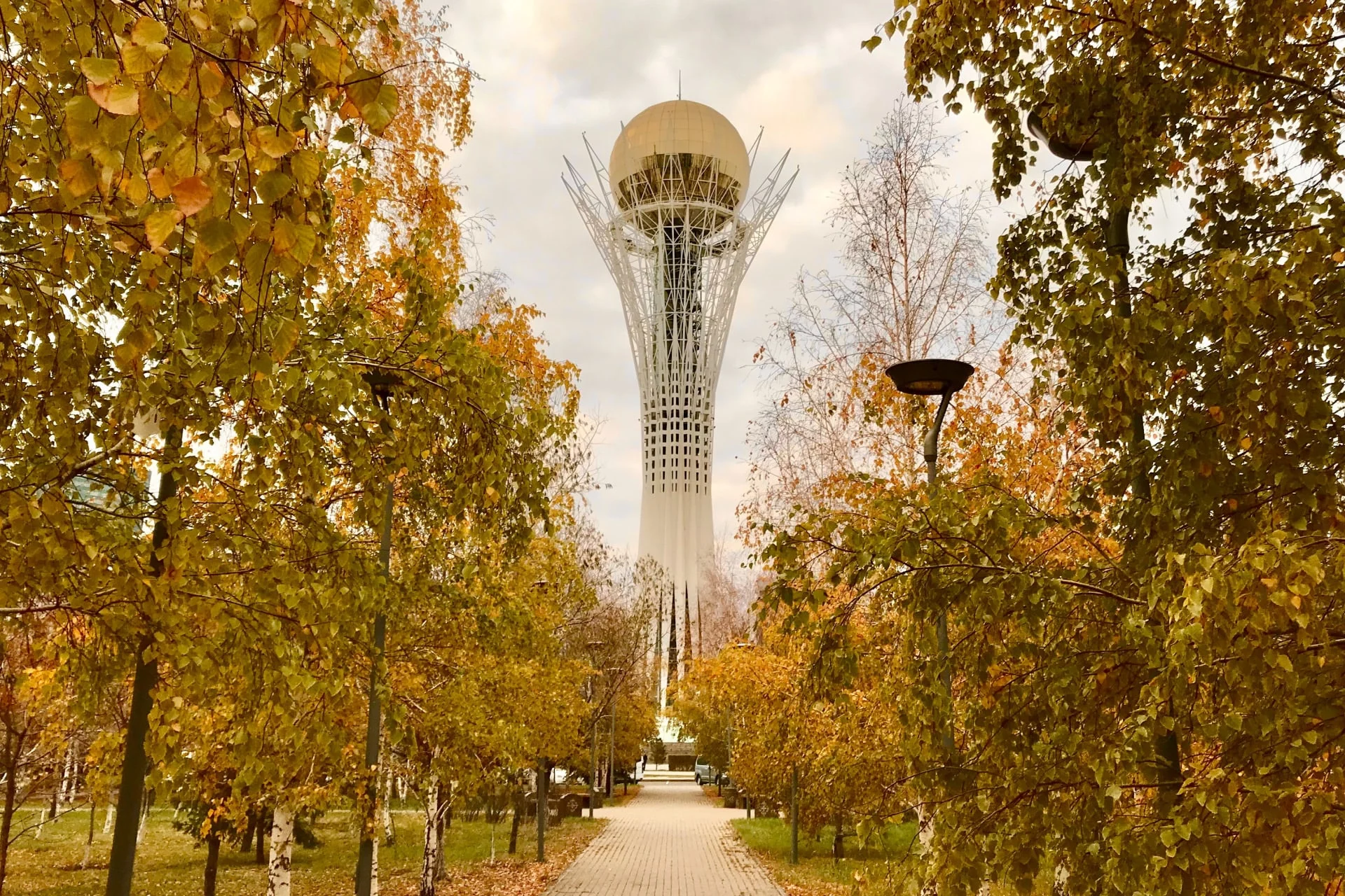 A tall tower in the middle of a park with trees.