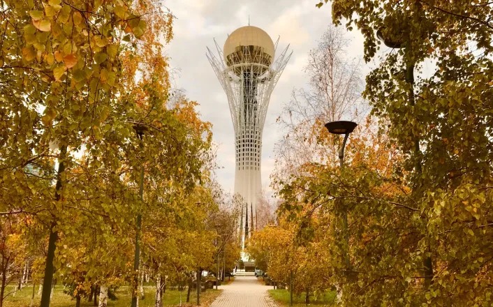 A tall tower in the middle of a park with trees.