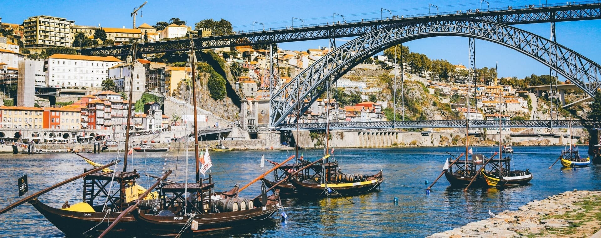 Boats docked under a bridge in porto, portugal.