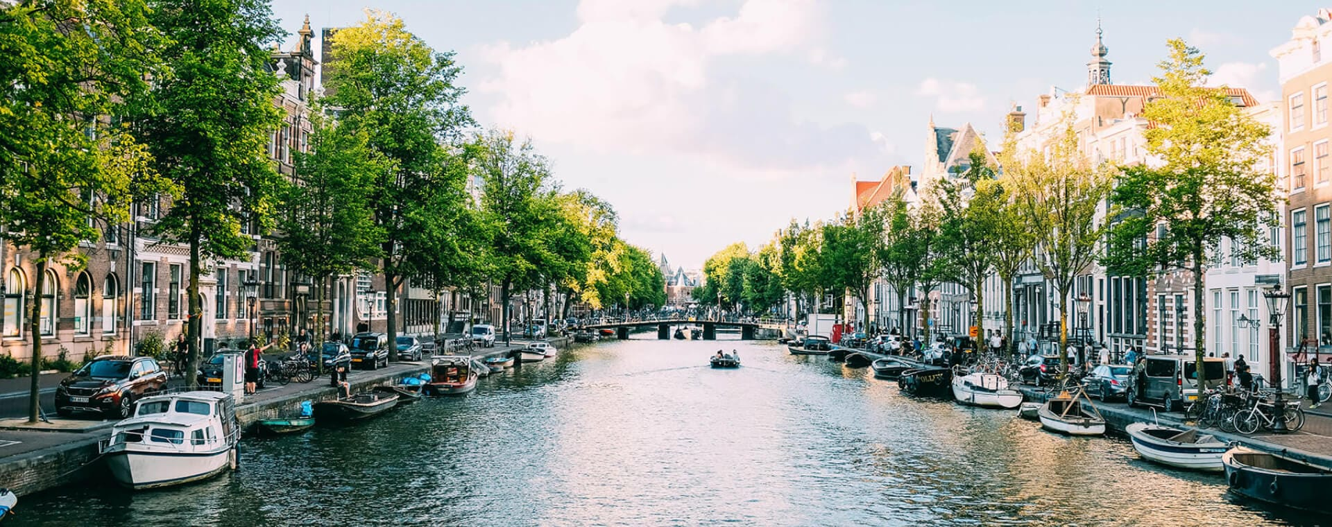 A canal lined with boats and trees in amsterdam.