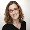 A woman with red glasses smiling for the camera.