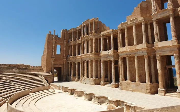 The ruins of an ancient theatre in a desert.