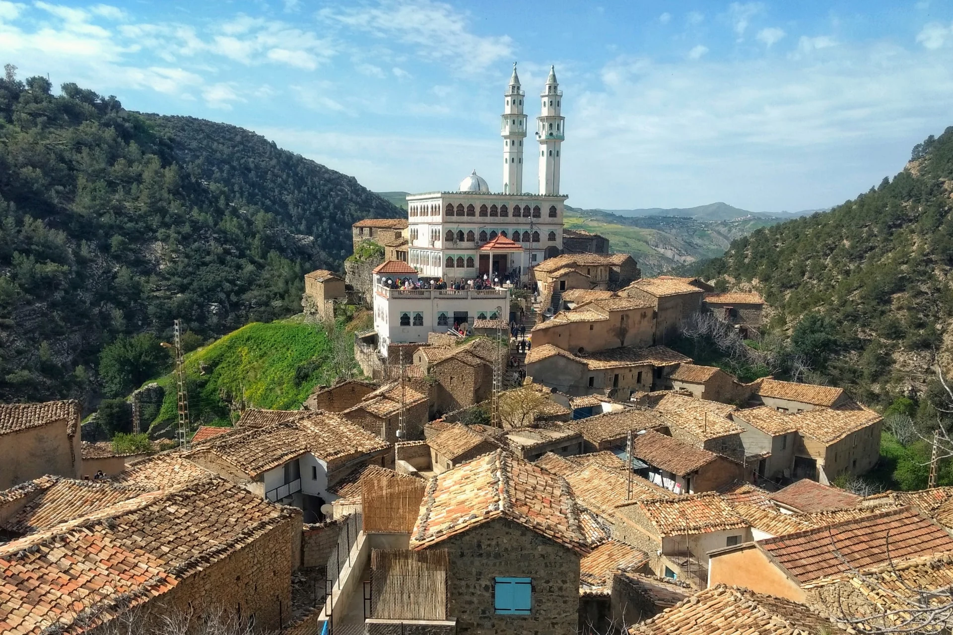 A village in the mountains with a mosque in the background.