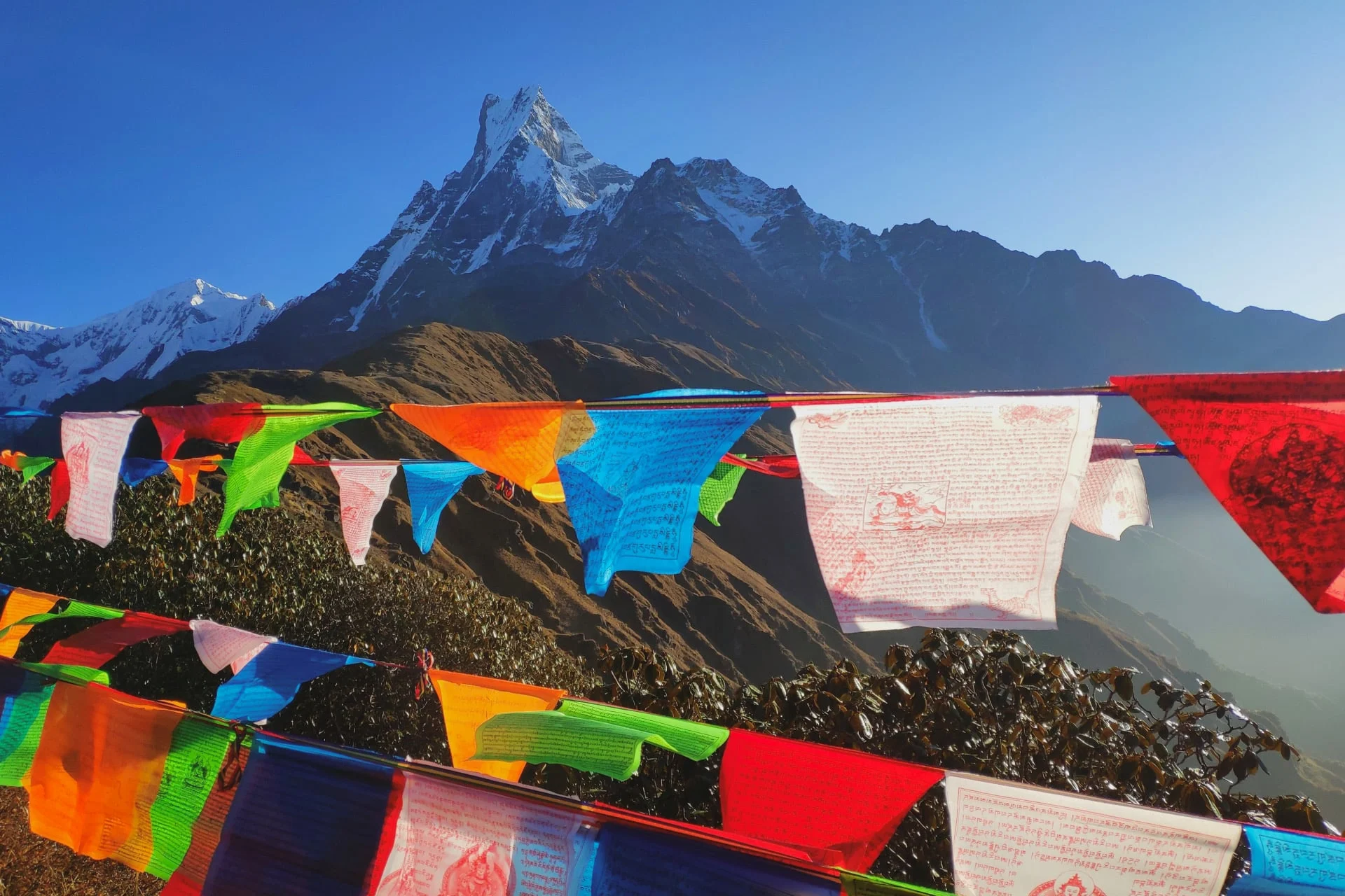 Prayer flags in front of a mountain with mountains in the background.