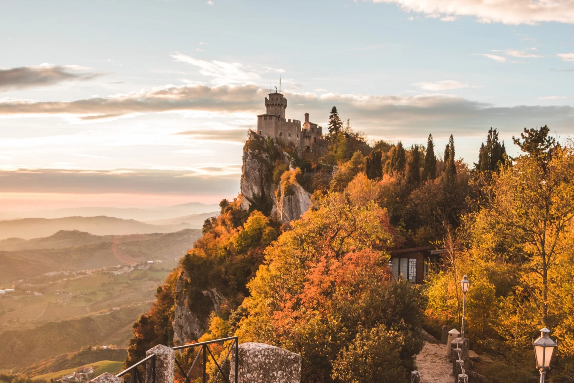 A castle sits on top of a mountain in the fall.