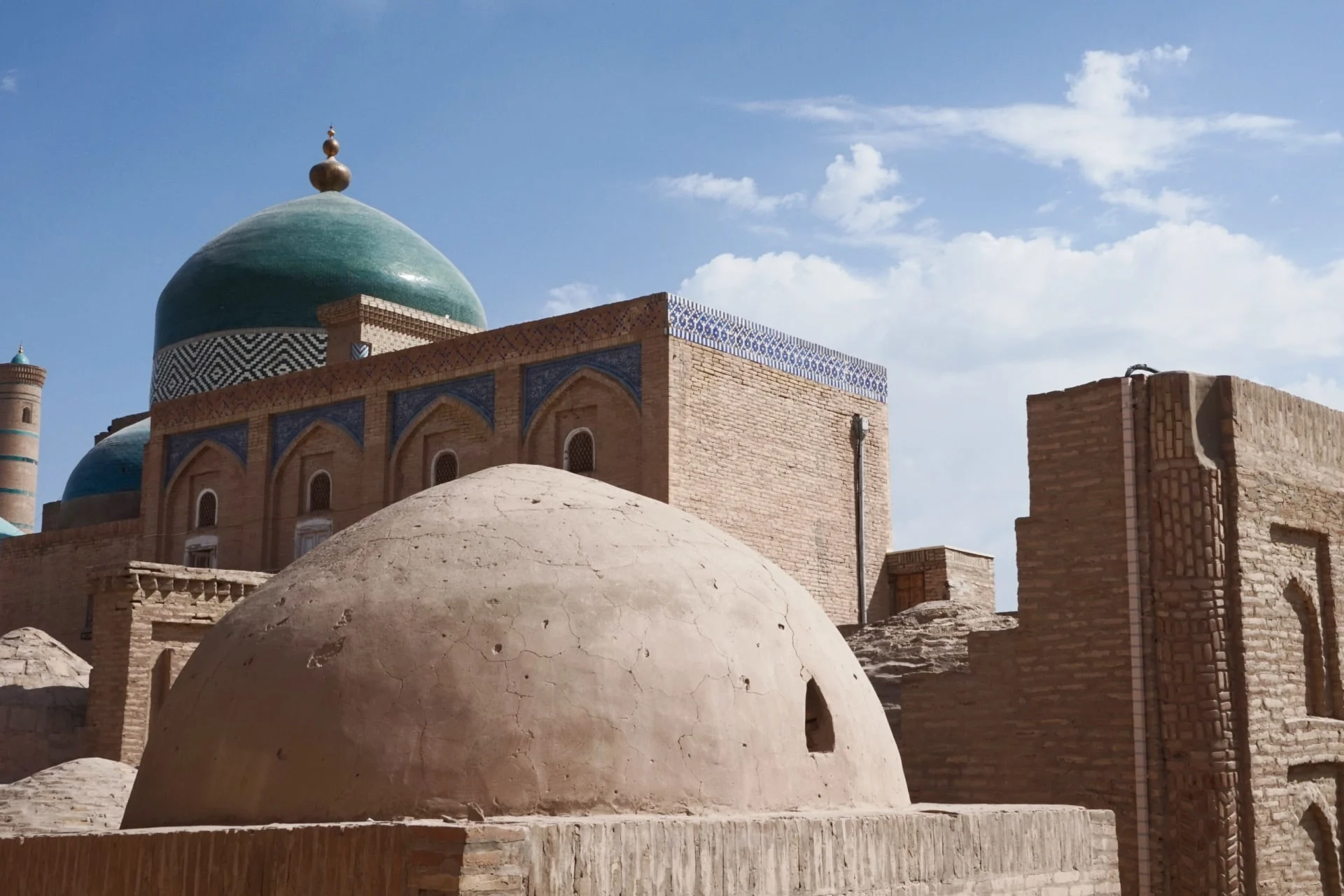 A mosque with green domes and a blue sky.