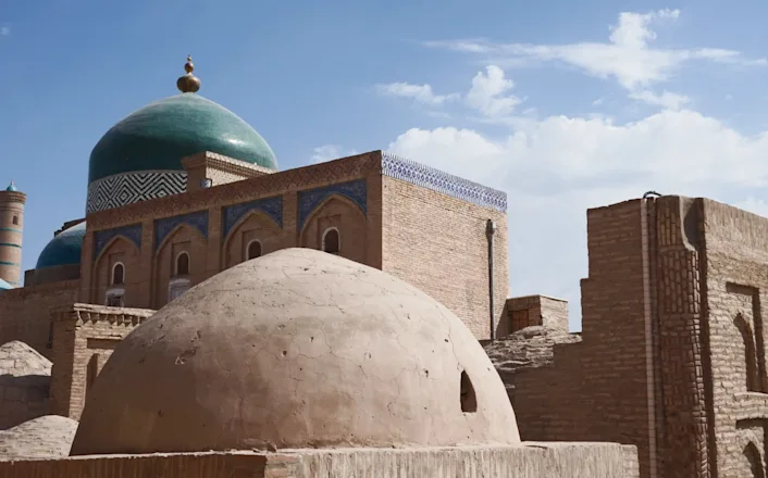 A mosque with green domes and a blue sky.
