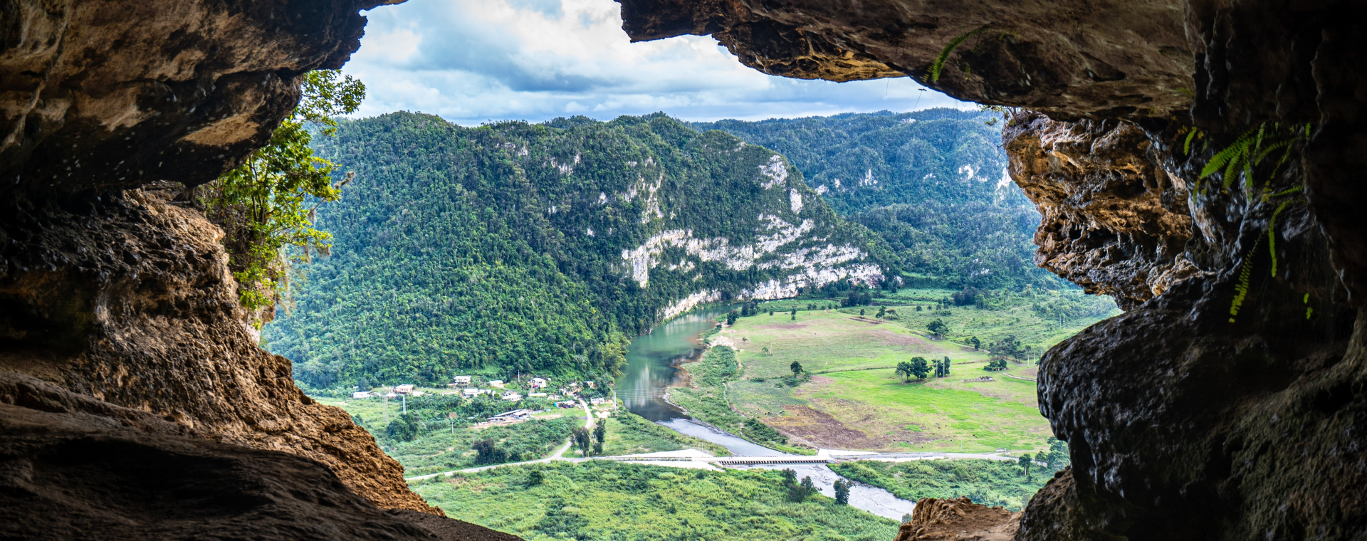 A cave with a view of a river and mountains.