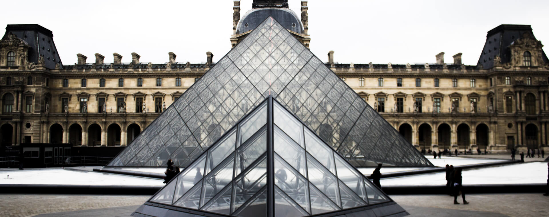 A large glass pyramid in front of a building.