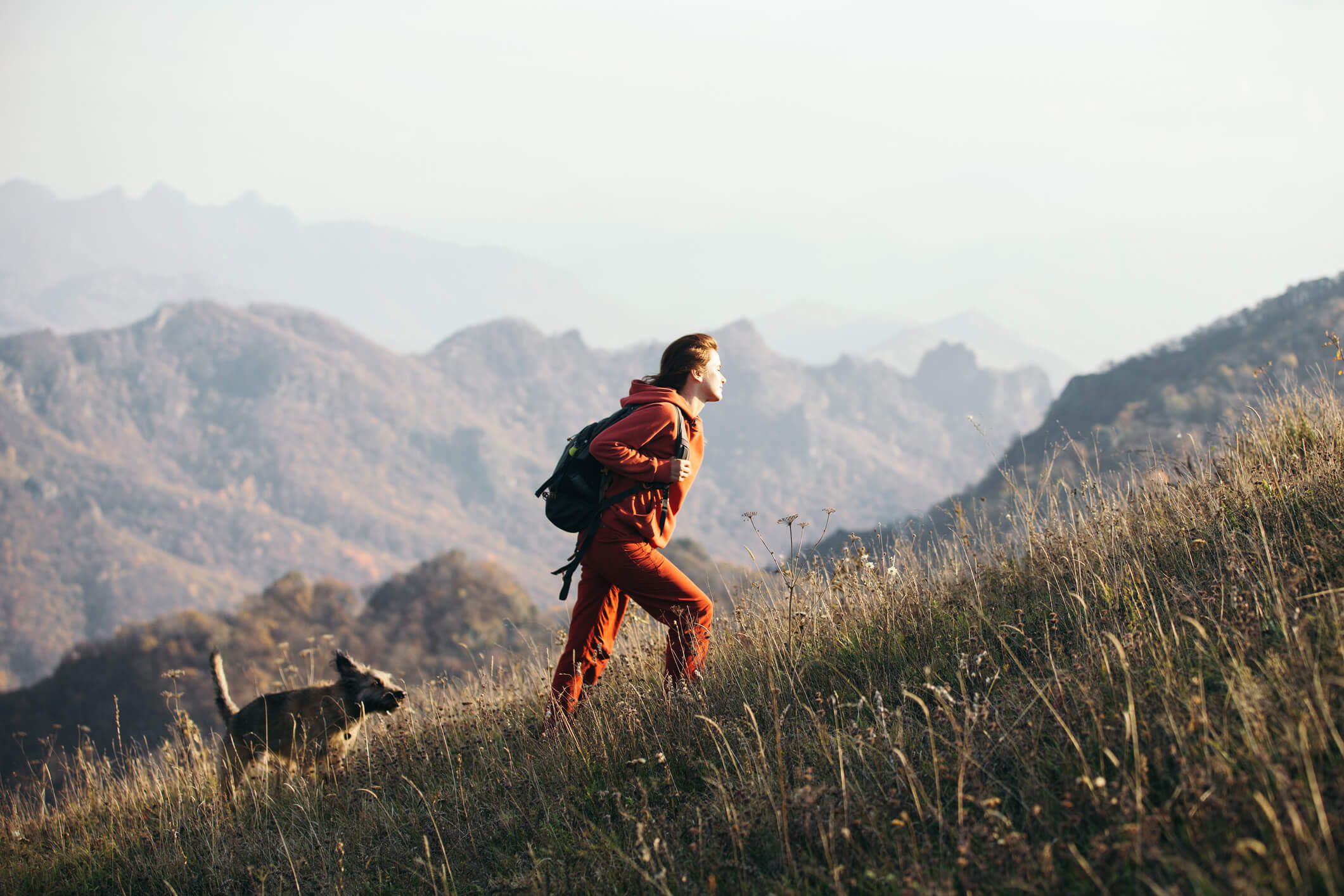 A woman hiking with her dog in the mountains.