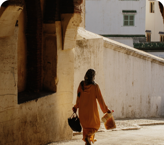 A woman in a yellow dress walking down a narrow alley.