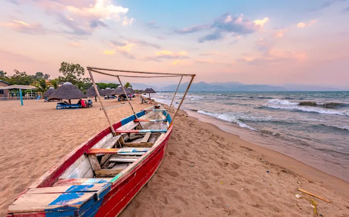 A red and blue boat sitting on a sandy beach.
