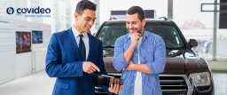 A sales representative uses a tablet to demonstrate a Video Sales Letter (VSL) to a potential customer at a car dealership. VSLs help create engaging, personalized experiences that build trust and drive sales.