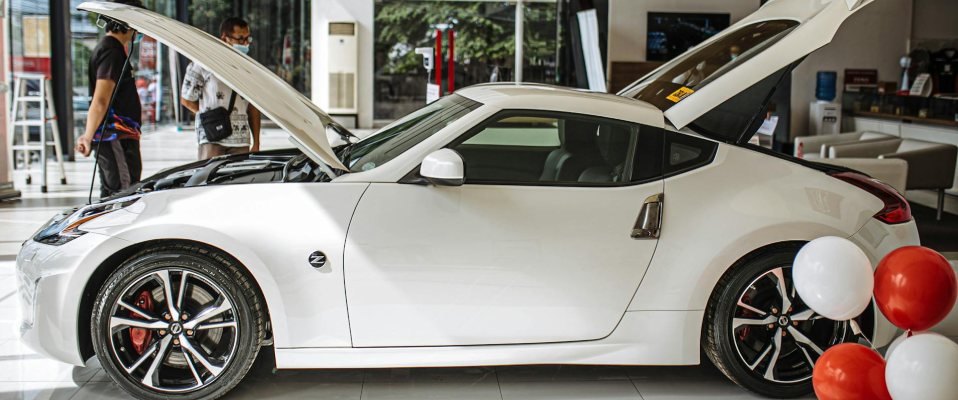 A photo of a white luxury car in a dealership showroom with red and white balloons