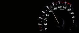 A black background with a picture of a car's speedometer, pointing around 80 mph
