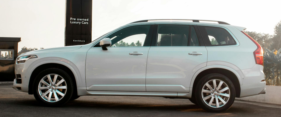 A photo of a white luxury SUV in front of a black sign that says "Pre-owned Luxury Cars"