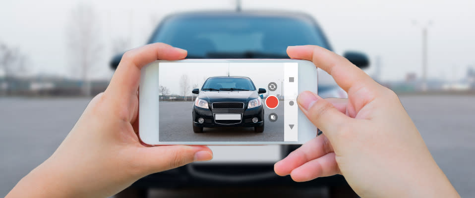 Image of salesperson at car dealership  holding a mobile phone and recording a vehicle walkaround video for the potential customer