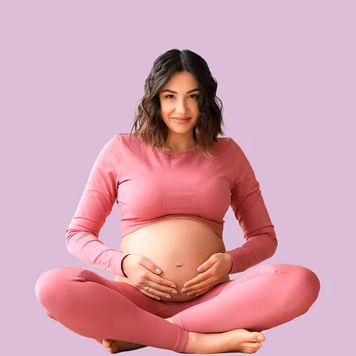 Smiling pregnant woman sitting and holding her belly with her hands