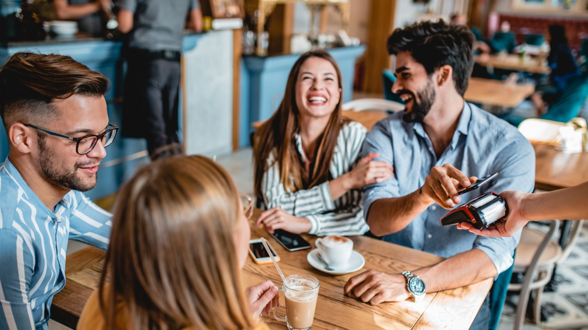 A group of friends at a cafe paying for lunch.