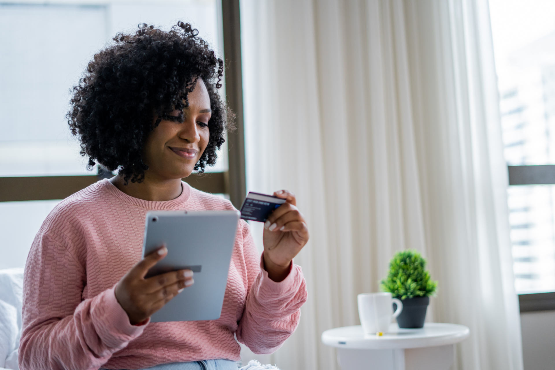 Woman holding a tablet while looking at her credit card